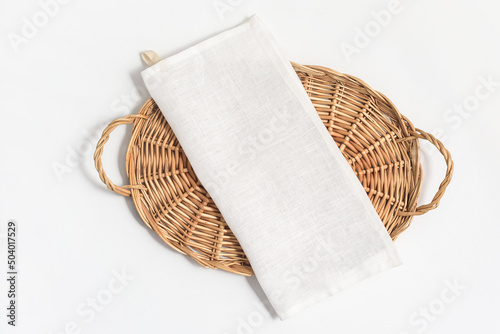 Flatlay composition with natural linen kitchen tea towel or napkin on wicker tray on white background