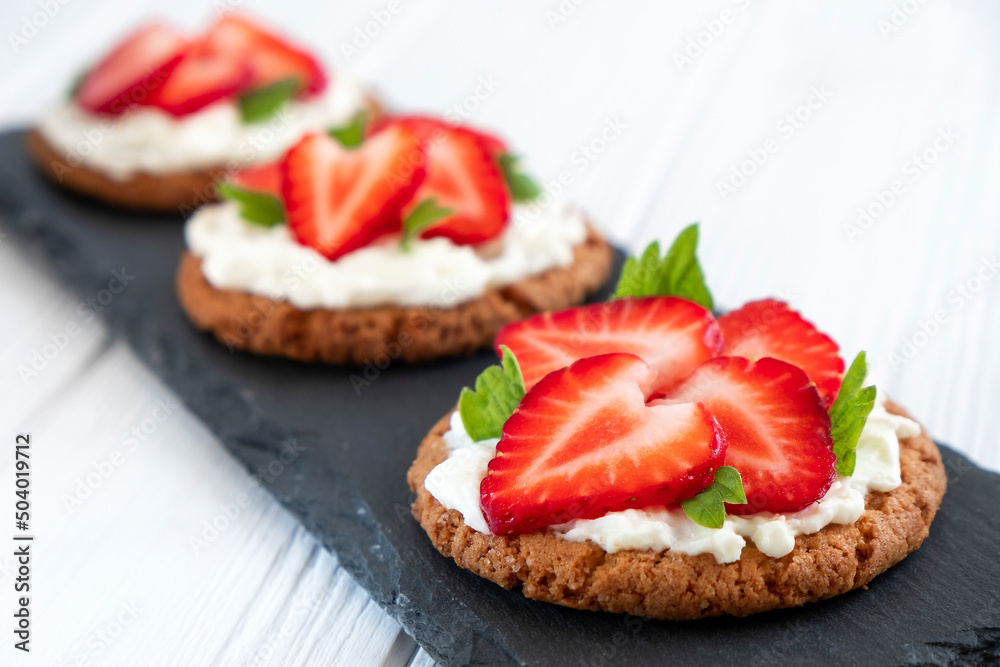 Healthy toast with strawberry, cream cheese and mint leaf. Tasty breakfast. Clean eating, dieting or recipe of healthy snack sandwich for vegetarian. Restaurant serving on slate board.