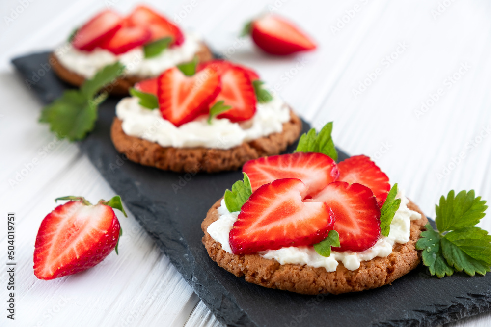 Healthy crispbread bruschetta with strawberry and cream cheese on slate board. Healthy snack, clean eating or dieting concept. Recipe of vegan food for everyday cooking. Healthy crispbread bruschetta with strawberry and cream cheese on slate board. Healthy snack, clean eating or dieting concept. Recipe of vegan food for everyday cooking.