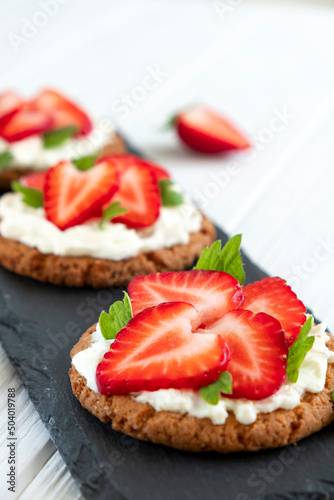 Strawberry bruschetta on rye bread with cottage cheese and mint. Healthy snack, keto diet or dieting concept. Recipe of vegan food for everyday cooking.