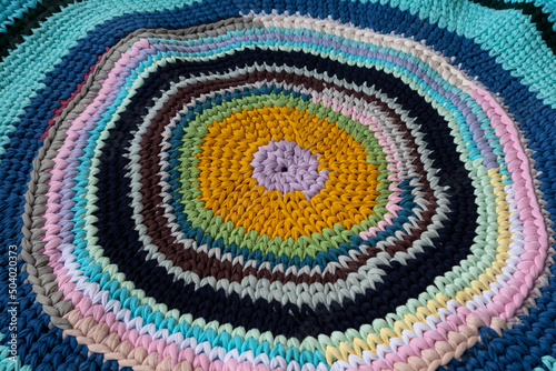 The mat is made of knitted yarn, hand-knitted on knitting needles. Home needlework.