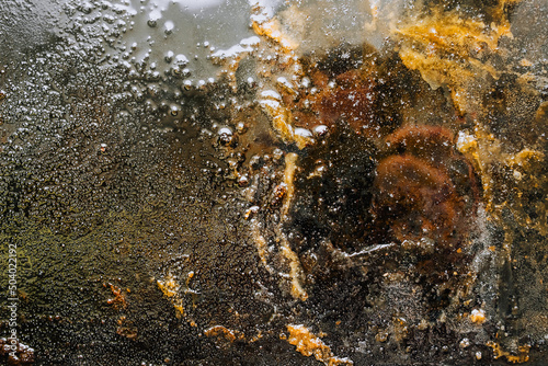 Texture  background  top view of a black tray smeared in fat  oil  pieces of old meat  after cooking. Food photography  abstraction  top view.