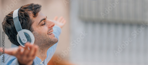 happy young man with headphones listening to music outdoors