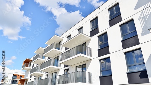 Fotografie, Obraz Part of a white residential building  with balconies and blue sky with clouds