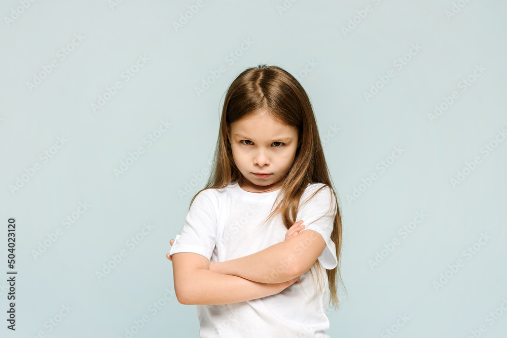 Photo of unhappy sad upset little girl feeling bored offended isolated on blue background Photo of unhappy sad upset little girl feeling bored offended isolated on blue background