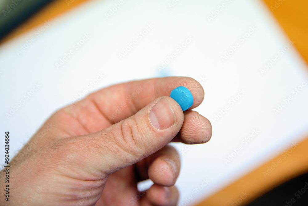 A blue pill in the man's hand.
