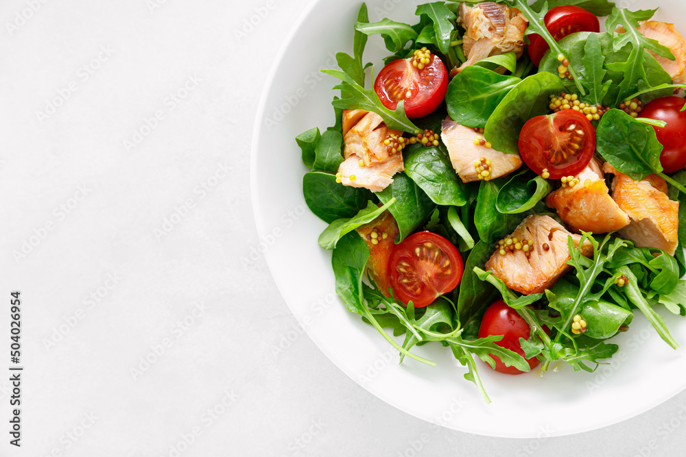 Grilled salmon salad with tomato and salad mix. Top view