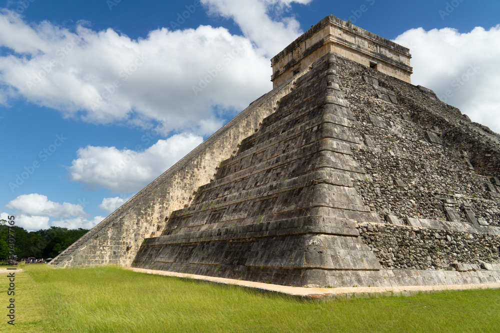 Pyramid Kukulkan, Chichen Itza, Mexico, Mayan archeological site. Famous 7 wonders of the world, UNESCO heritage. Partially destroyed pyramid on green grass.