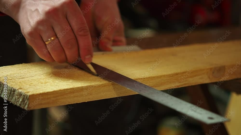 the carpenter measures and marks the wood in the workshop to cut the carpenter measures and marks the wood in the workshop to cut