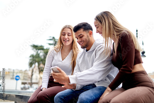 Mixed group of friends looking at the phone in the street
