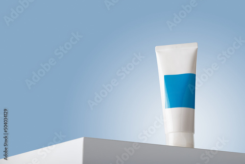 White care cosmetics tube with blue blank label mockup, face skin cream or mineral tooth paste container template on white table podium