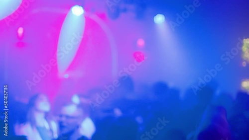 Blurry background footage: Many drunk and happy people partying and clubbing in a nightclub photo