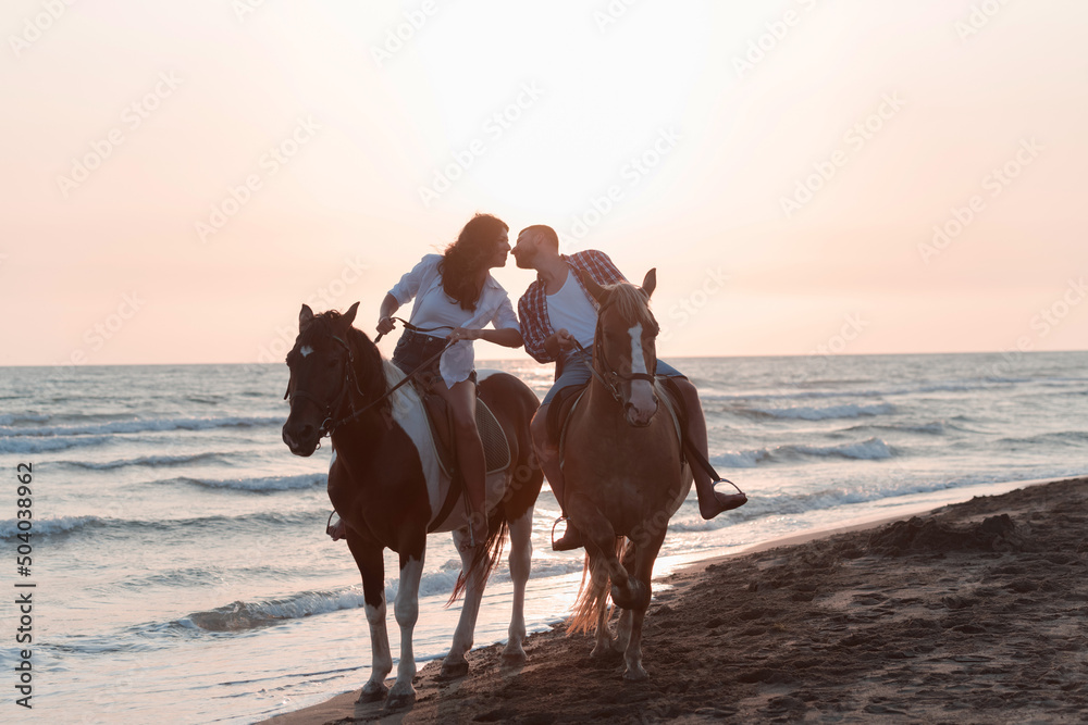 a loving couple in summer clothes riding a horse on a sandy beach at sunset. Sea and sunset in the background. Selective focus a loving couple in summer clothes riding a horse on a sandy beach at sunset. Sea and sunset in the background. Selective focus