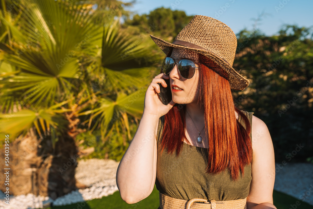 young red-haired woman travelling, calls her family on her mobile phone when she arrives at her holiday destination. young red-haired woman travelling, calls her family on her mobile phone when she arrives at her holiday destination.