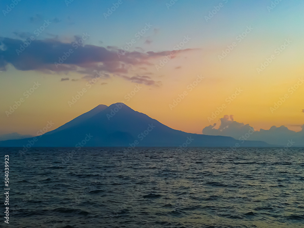 sunset between lake and volcanoes