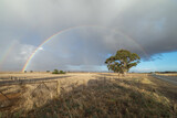 Full rainbow over South Australian farming coulntryside. Road trip landscape with dramatic moody clouds