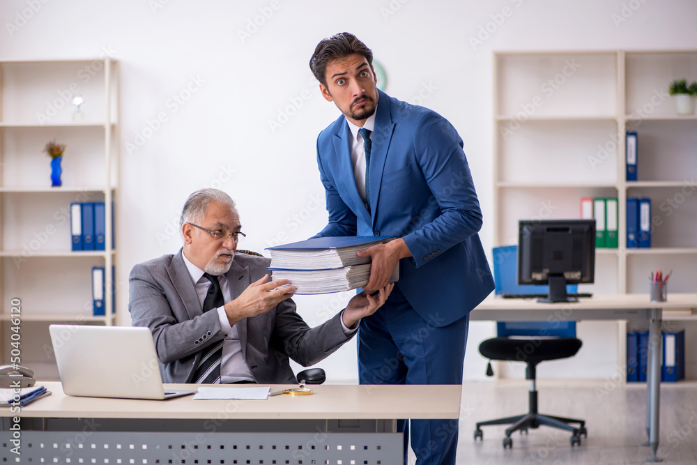Old male boss and young male employee working in the office Old male boss and young male employee working in the office