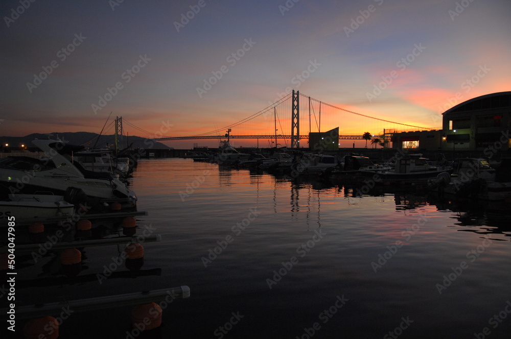 夕焼けがセンチメンタルな港の夕暮れ。橋と船が見えるハーバー。