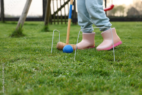 Fotografie Girl playing croquet on green grass outdoors, closeup