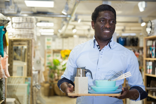 Man customer holding purchases and walking in a household goods store