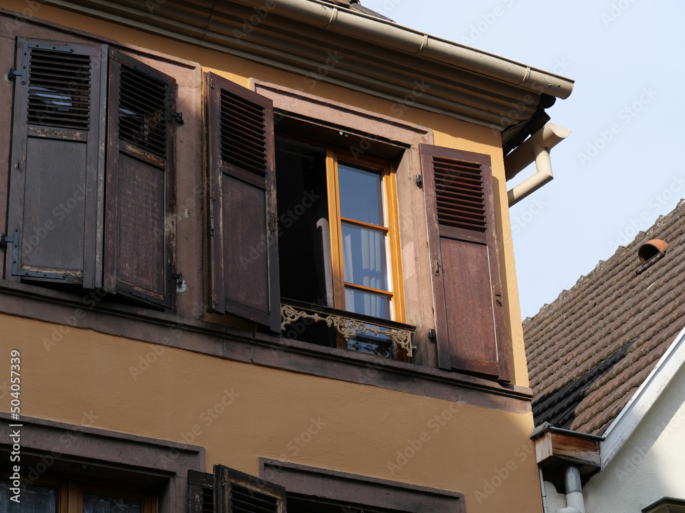 Geöffnetes Fenster mit brauenen Fensterläden am Eck eines alten Hauses im Elsass
