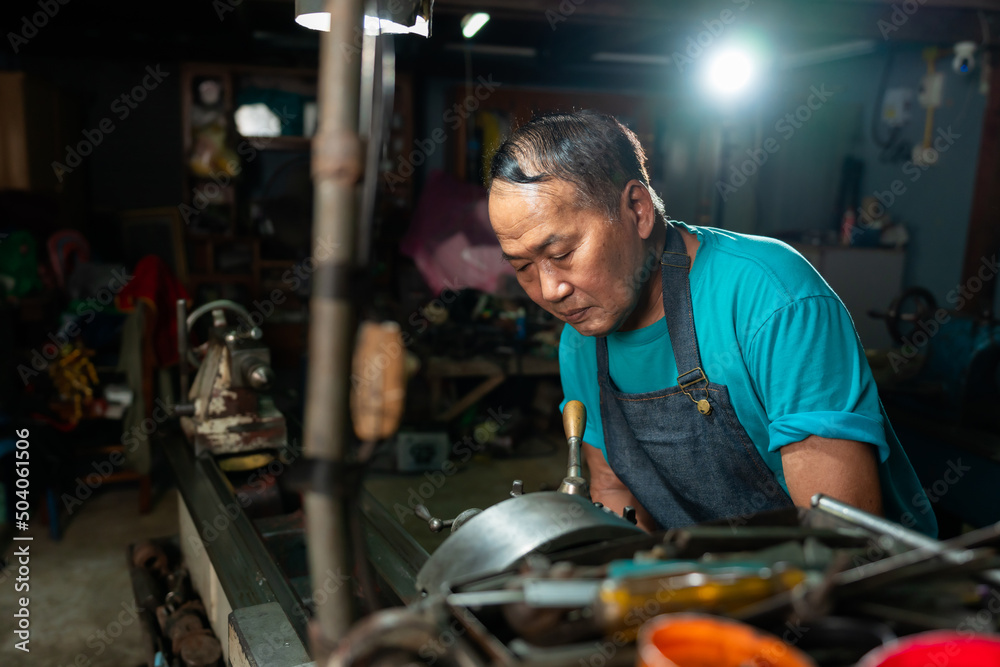 The senior mechanic has a serious expression, in operation, and controls the lathe, closely and very carefully. The senior mechanic has a serious expression, in operation, and controls the lathe, closely and very carefully.