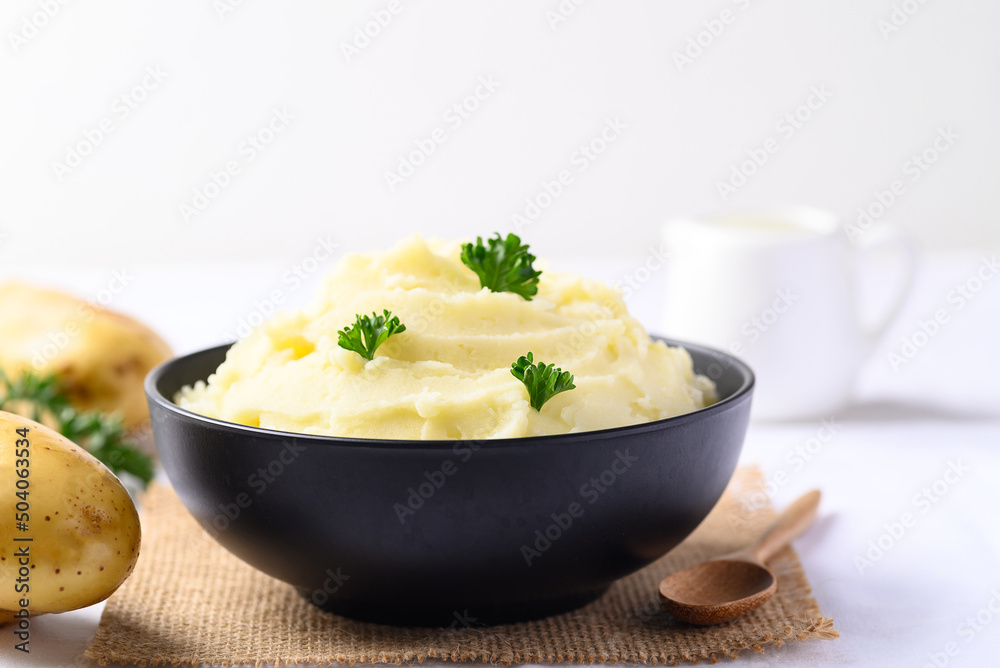 Mashed potato with parsley in black bowl on white background Mashed potato with parsley in black bowl on white background