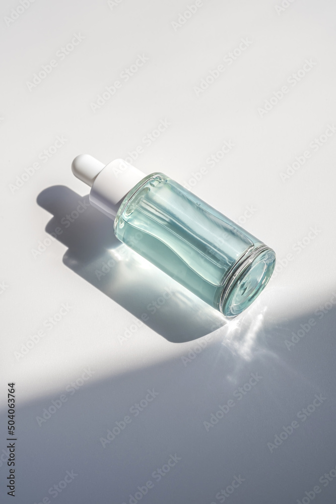 A blue transparent bottle with serum in the rays of the sun. A blue transparent bottle with serum in the rays of the sun.