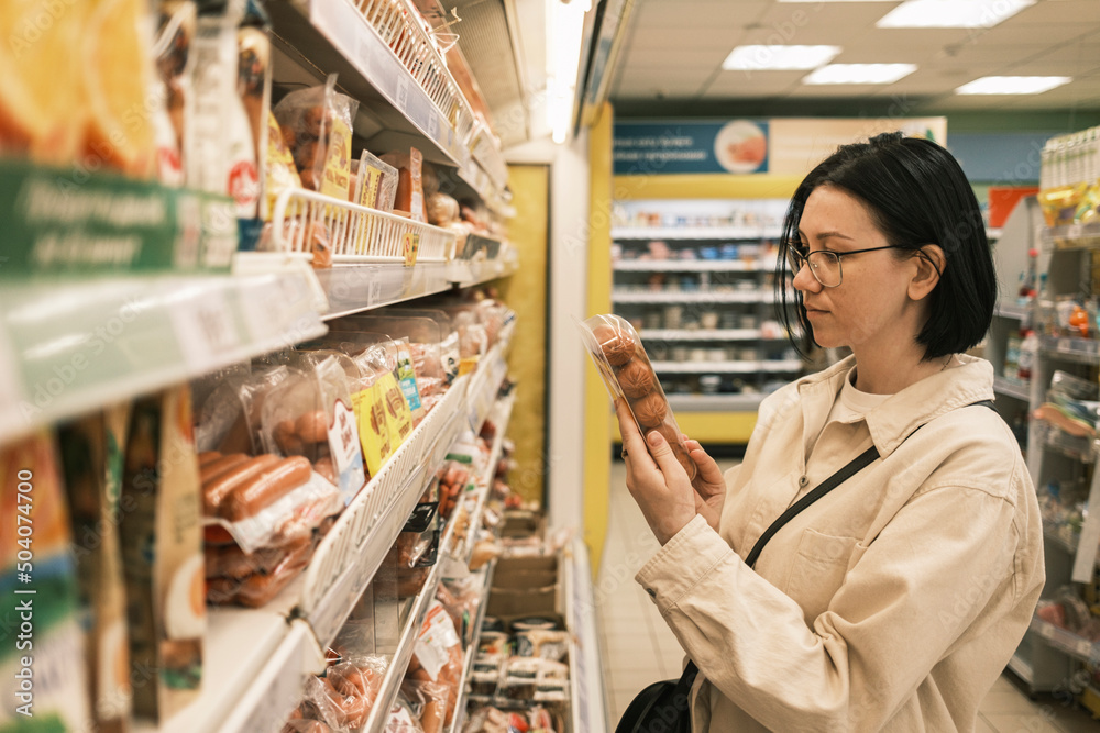 A young woman in a grocery supermarket chooses food. Shopping concept