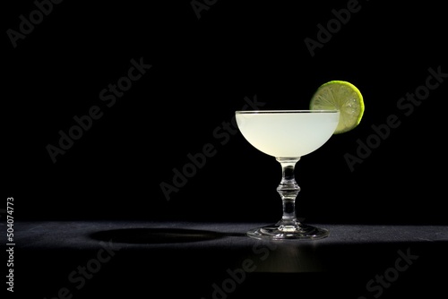 Gimlet gin cocktail, lime garnish agains a black background photo