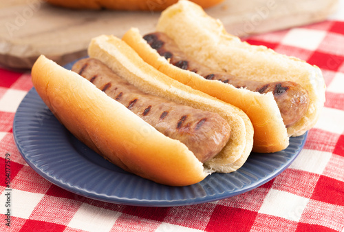 Grilled Bratwurst in a Bun on a Red and White Table photo