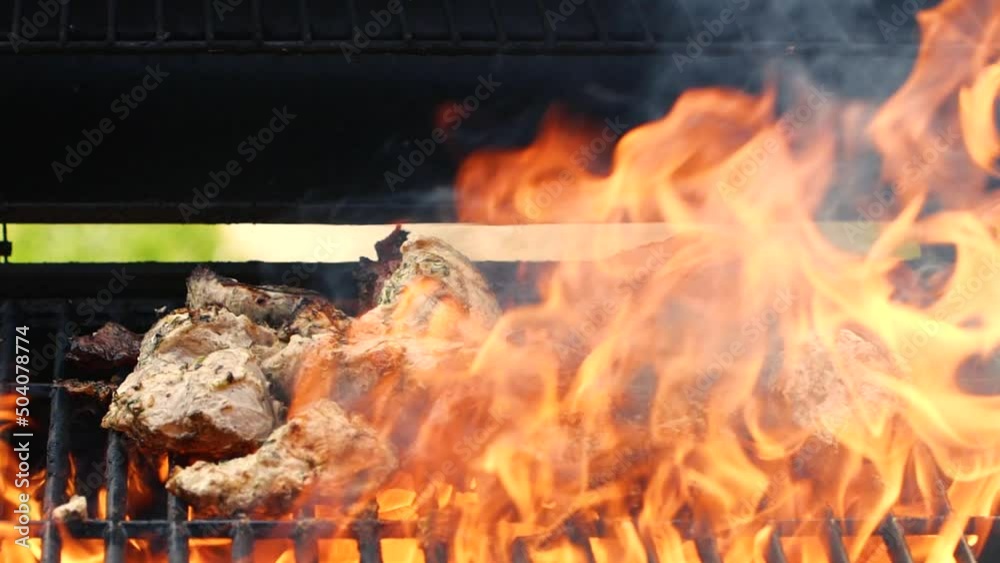 Close-up cooking meat on barbecue grilll, slow motion burning fire flame, smoke Close-up cooking meat on barbecue grilll, slow motion burning fire flame, smoke