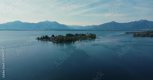 Beautiful 4k aerial drone shot of small island Fraueninsel surrounded by blue lake Chiemsee in Gstadt, Chiemgau, Bavaria with bavarian and austrian alps in background. photo
