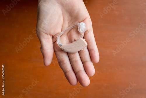 Electronic hearing aid device in the ear of Asian woman with total deafness. photo