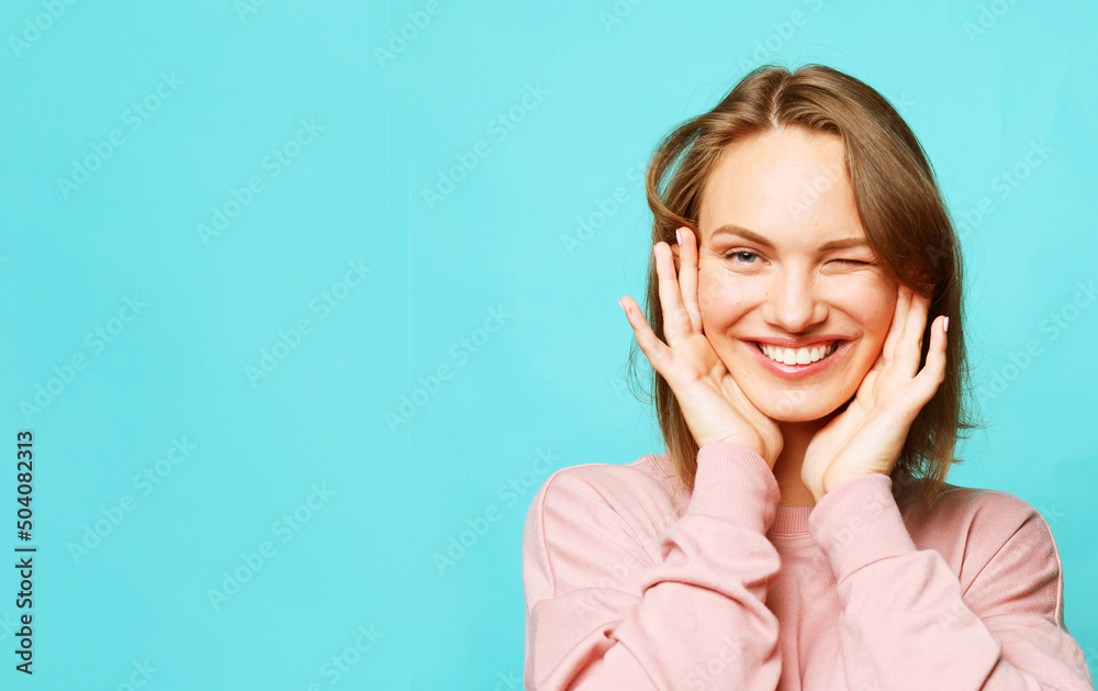 Lifestyle and people concept. Young happy smiling blond female with short hair wear pink sweater over blue background. Lifestyle and people concept. Young happy smiling blond female with short hair wear pink sweater over blue background.