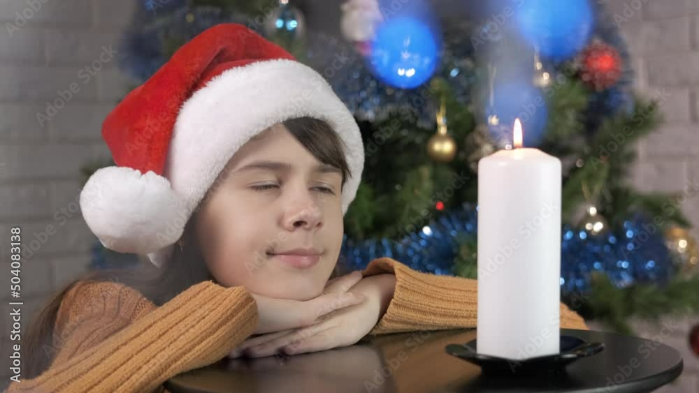 Dreaming teen Christmas night with candle. A view of dreaming teen girl by the big white candle on the table during Christmas night.