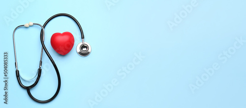 Foto Stethoscope and red heart on light blue background with space for text