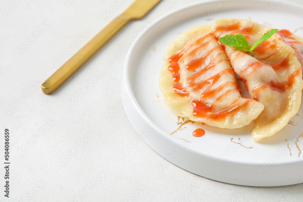 Plate with tasty strawberry dumplings and jam on light background, closeup Plate with tasty strawberry dumplings and jam on light background, closeup