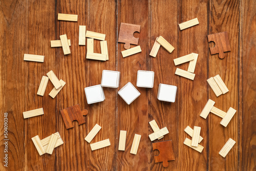 Cubes with blocks and puzzle pieces on wooden background
