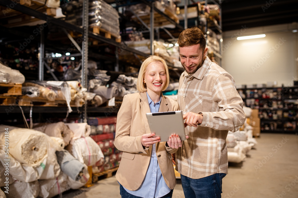 Two business people checking the list and inventory on a tablet. Businesswoman sharing the stock details with warehouse manager.