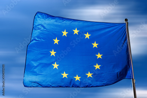 Close-up of an European Union flag waving against a clear blue sky with clouds and copy space.