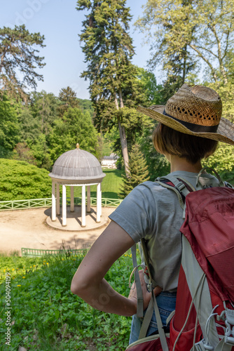 Hiking Woman with brown hair, gray t-shirt, straw hat and red backpack looking at Freundschaftstempel temple, Staatspark F�rstenlager, Auerbach, Bensheim, Germany photo