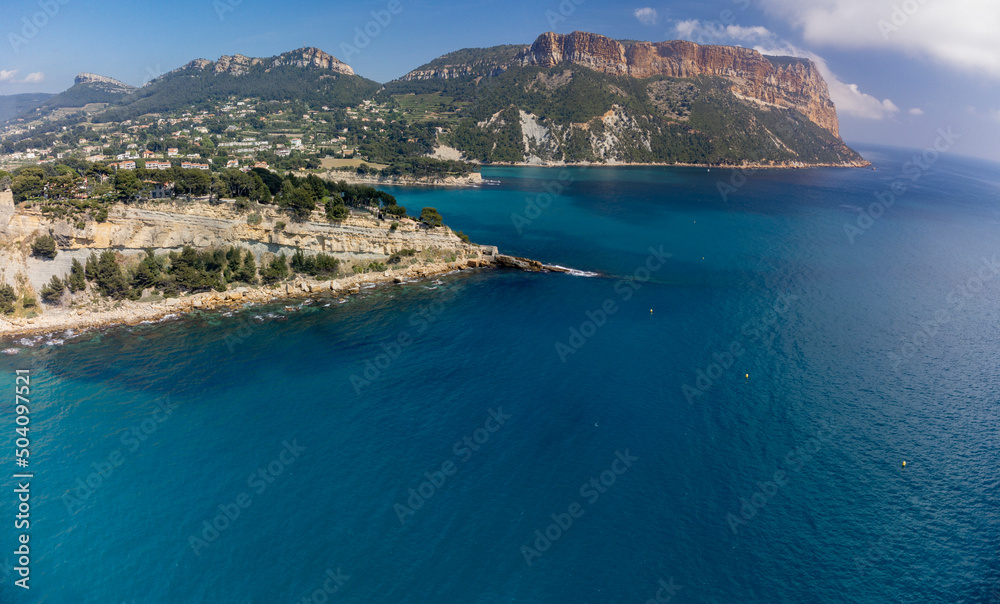 Panoramic aerial view on cliffs, blue sea, beach, houses, streets and old fisherman's harbour with lighthouse in Cassis, Provence, France