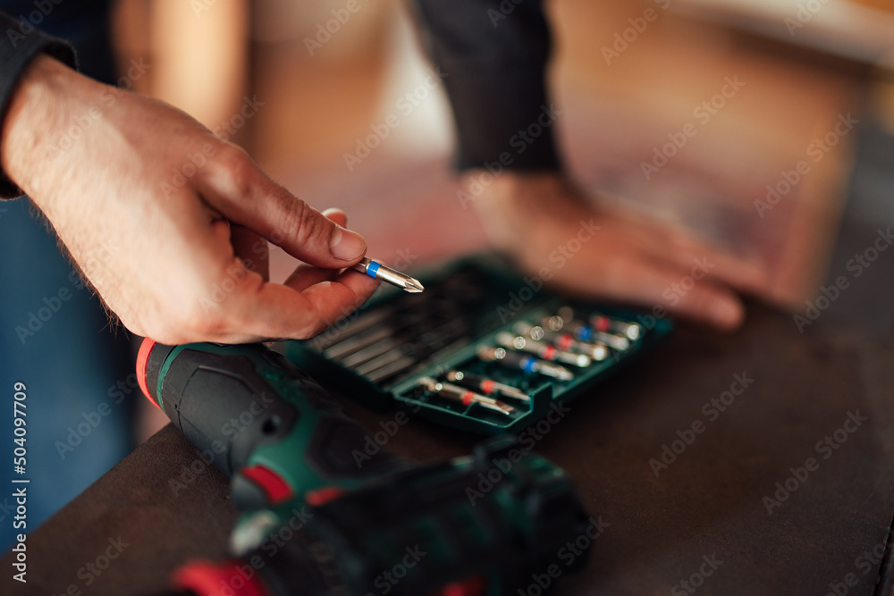 Close up of male hands holding a drill bit, leaning on the desk. Close up of male hands holding a drill bit, leaning on the desk.
