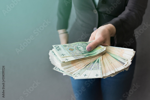 Kobieta wyciąga przed siebie ręce pełne pieniędzy, dużo pieniędzy w dłoni