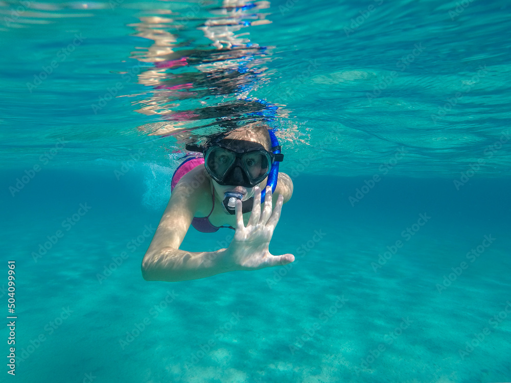 Young Woman Snorkeling In Clear Turquoise Water And Looking At Camera