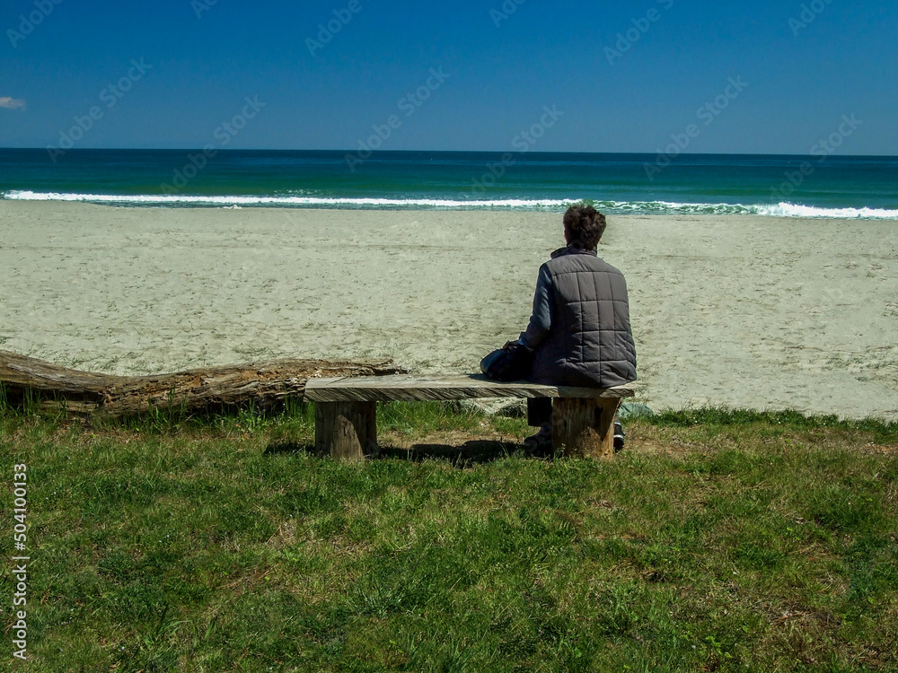 Lonely Senior Woman Sitting On Bench On The Beach