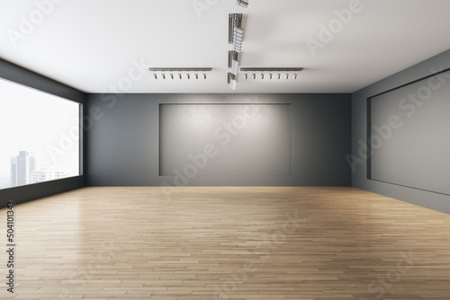 Contemporary empty concrete gallery interior with window and city view, wooden flooring, mock up place on walls and daylight. Museum concept. 3D Rendering.