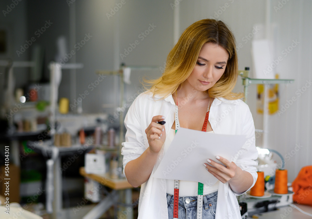Young beautiful blonde hair worker in defocus holding a phone with a green screen on a light background. Young beautiful blonde hair worker in defocus holding a phone with a green screen on a light background.
