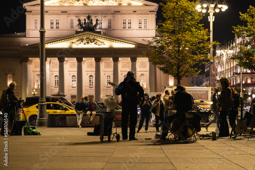 A guitarist plays in front of the Bolshoi Theater in Moscow at night
